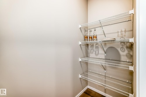 Corner pantry featuring three levels of wire shelving, light neutral wall paint, and wood-finish flooring - 1603 206 Street, Edmonton, AB - Indoor With Storage