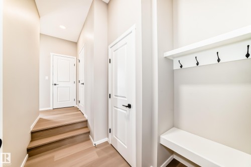 Entryway featuring a built-in bench with integrated coat hooks, recessed lighting, wood-finish flooring, two-panel interior doors, and matte black hardware - 1603 206 Street, Edmonton, AB - Indoor Photo Showing Other Room
