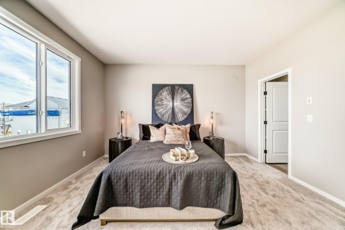 Carpeted bedroom featuring neutral wall tones, a large window with white trim, and a white interior door with black hardware - 1603 206 Street, Edmonton, AB - Indoor Photo Showing Bedroom