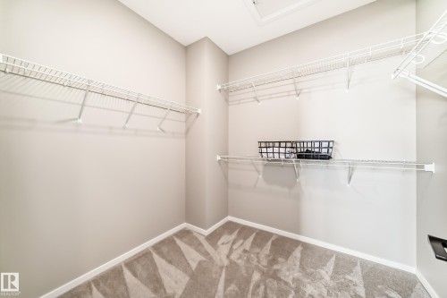 Walk-in closet featuring wire shelving, white baseboards, light neutral wall paint, and a patterned carpet - 1603 206 Street, Edmonton, AB - Indoor With Storage