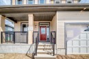 Exterior facade featuring a covered porch, concrete steps with black railings, a red entry door with sidelights, and horizontal siding - 1603 206 Street, Edmonton, AB  - Outdoor 