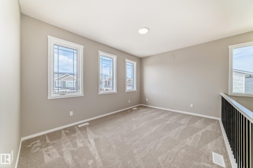 Spacious room featuring neutral carpeting, light neutral wall paint, and white trim throughout - 1603 206 Street, Edmonton, AB - Indoor Photo Showing Other Room