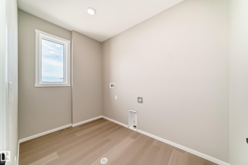 Laundry room with wood-finish flooring, recessed lighting, and a white-framed window - 1603 206 Street, Edmonton, AB - Indoor Photo Showing Other Room