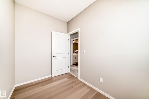 Neutral-toned room featuring light wood-finish flooring and a white trim baseboard - 1603 206 Street, Edmonton, AB - Indoor Photo Showing Other Room