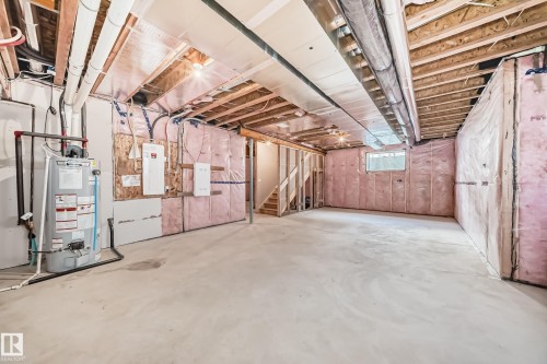 Unfinished basement featuring exposed wood joists, concrete flooring, a water heater, visible electrical panels, and insulation on perimeter walls - 1603 206 Street, Edmonton, AB - Indoor Photo Showing Basement