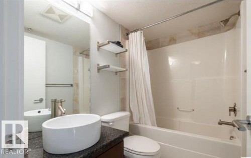 Bathroom featuring a white oval vessel sink, dark countertop, and large wall mirror - 702 10055 118 Street, Edmonton, AB - Indoor Photo Showing Bathroom