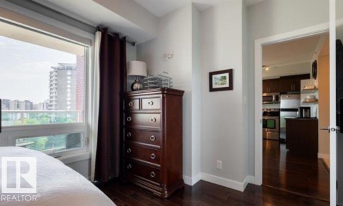 Hardwood-finish flooring throughout, complemented by light-toned wall paint and white baseboards - 702 10055 118 Street, Edmonton, AB - Indoor Photo Showing Bedroom