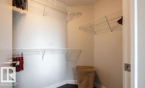 Walk-in closet featuring white wire shelving, dark wood-finish flooring, and light neutral wall paint - 702 10055 118 Street, Edmonton, AB - Indoor With Storage