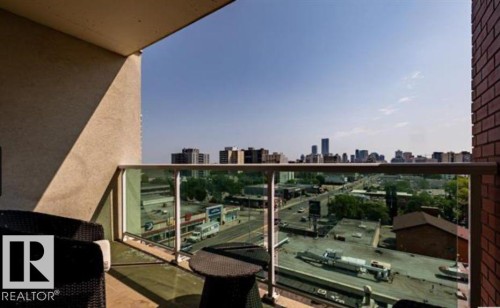 Private balcony featuring a glass railing system and a brick-finish exterior wall - 702 10055 118 Street, Edmonton, AB - Outdoor With Balcony With Exterior