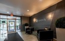 Contemporary lobby featuring a glass entry system, recessed lighting, wall sconces, and a dark accent wall with decorative paneling - 702 10055 118 Street, Edmonton, AB  - Indoor Photo Showing Other Room 