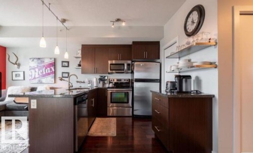 Modern kitchen featuring dark wood-finish cabinetry and stainless steel appliances - 702 10055 118 Street, Edmonton, AB - Indoor Photo Showing Kitchen