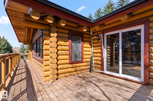 Expansive log home deck with wood railing, featuring a sliding glass door entry and additional window openings - A & B, 4858 Centre St, New Sarepta, AB - Outdoor With Deck Patio Veranda With Exterior