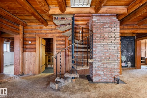 Spiral staircase with wrought iron railing and carpeted treads - A & B, 4858 Centre St, New Sarepta, AB - Indoor Photo Showing Other Room