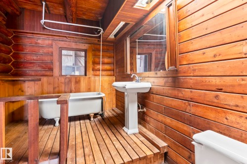 Bathroom featuring a freestanding clawfoot tub, pedestal sink, and wood plank flooring - A & B, 4858 Centre St, New Sarepta, AB - Indoor Photo Showing Other Room