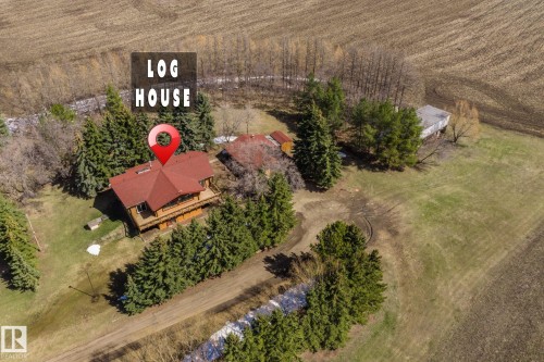 Log house with a red roof, surrounded by mature evergreen trees - A & B, 4858 Centre St, New Sarepta, AB - Outdoor With View