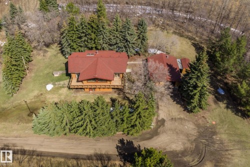 A-frame property with a red-shingled roof and wood-clad exterior, featuring an elevated deck and surrounding evergreen trees - A & B, 4858 Centre St, New Sarepta, AB - Outdoor With View