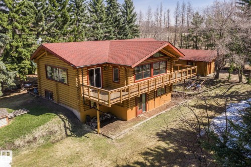 Log-style home featuring a red shingle roof, extensive wrap-around deck with wood railings, multiple large windows, and a lower-level walkout - A & B, 4858 Centre St, New Sarepta, AB - Outdoor With Deck Patio Veranda