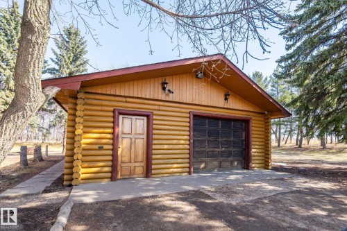 Log cabin-style detached garage featuring a single bay, a separate entry door, and exterior lighting fixtures - A & B, 4858 Centre St, New Sarepta, AB - Outdoor