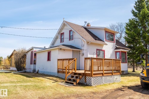 White stucco exterior with red trim accents and a brown shingle roof - A & B, 4858 Centre St, New Sarepta, AB - Outdoor With Deck Patio Veranda