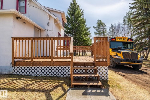 Expansive wooden deck featuring sturdy railings and lattice skirting, offering direct access to the exterior of the property - A & B, 4858 Centre St, New Sarepta, AB - Outdoor