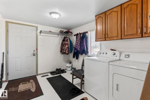 Utility room featuring white walls, wood-finish cabinetry, a white paneled door, and a horizontal window with blinds - A & B, 4858 Centre St, New Sarepta, AB - Indoor Photo Showing Laundry Room