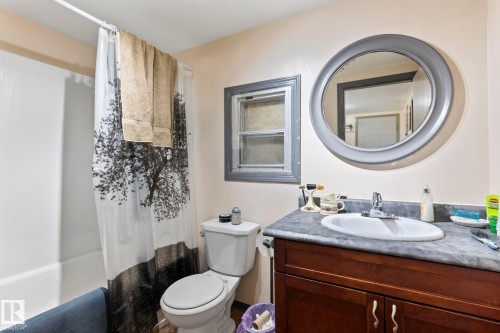 Bathroom featuring a white bathtub and shower surround, a white toilet, and a vanity with a dark wood-finish base and a gray countertop with an integrated white sink - A & B, 4858 Centre St, New Sarepta, AB - Indoor Photo Showing Bathroom