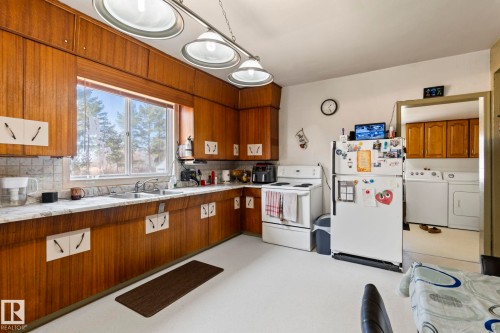 Kitchen featuring wood-finish cabinetry, white countertops, and a double basin sink - A & B, 4858 Centre St, New Sarepta, AB - Indoor Photo Showing Kitchen With Double Sink