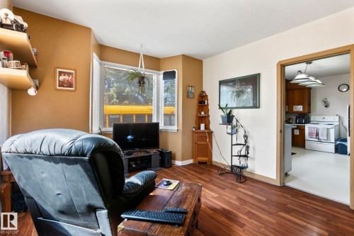 Living area featuring wood-finish flooring, corner windows, and a doorway opening to the kitchen - A & B, 4858 Centre St, New Sarepta, AB - Indoor Photo Showing Other Room