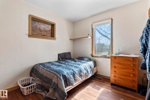 Room featuring wood-finish flooring, a window with a white blind, and a wood-framed decorative inset - A & B, 4858 Centre St, New Sarepta, AB - Indoor Photo Showing Bedroom