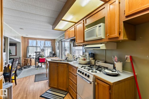 Kitchen featuring wood cabinetry, laminate countertops, a gas range, and wood-finish flooring - A & B, 4858 Centre St, New Sarepta, AB - Indoor Photo Showing Kitchen