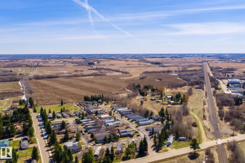 Aerial perspective showcasing a residential area bordered by cultivated fields and wooded sections - A & B, 4858 Centre St, New Sarepta, AB - Outdoor With View