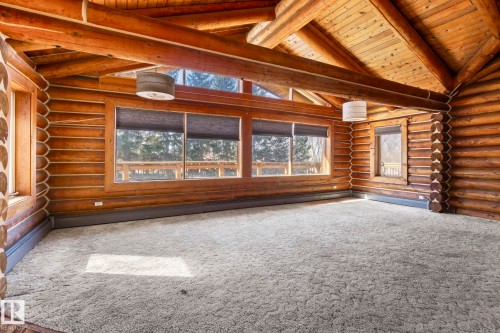 Vaulted ceiling featuring exposed wood beams, log construction walls, and light-colored carpeting - A & B, 4858 Centre St, New Sarepta, AB - Indoor Photo Showing Other Room