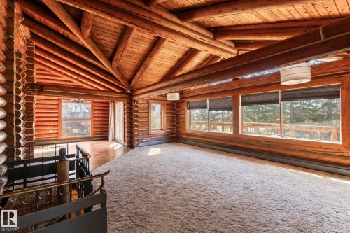 Room with exposed log walls and ceiling beams, featuring multiple windows, recessed lighting, and a section of wood-finish flooring - A & B, 4858 Centre St, New Sarepta, AB - Indoor Photo Showing Other Room