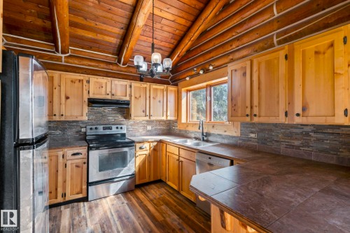 Kitchen featuring natural wood cabinetry, wood-finish flooring, and a tile backsplash - A & B, 4858 Centre St, New Sarepta, AB - Indoor Photo Showing Kitchen