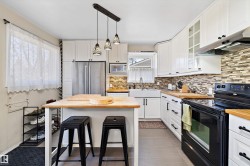 Kitchen featuring white cabinetry, butcher block countertops, a farmhouse sink, stainless steel refrigerator, and a mosaic tile backsplash - 