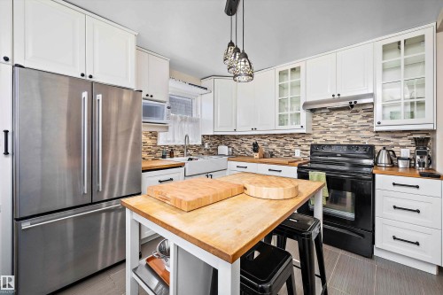Kitchen featuring white cabinetry, butcher block countertops, stainless steel French door refrigerator, black range, and tile backsplash - 11607 141 Street, Edmonton, AB - Indoor Photo Showing Kitchen With Stainless Steel Kitchen With Upgraded Kitchen