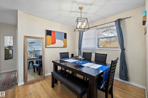 Dining area featuring wood-finish flooring, a contemporary chandelier, and a window with blinds - 11607 141 Street, Edmonton, AB - Indoor Photo Showing Dining Room