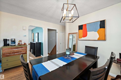 Open-concept dining area featuring wood-finish flooring, a contemporary ceiling light fixture, and arched doorways - 11607 141 Street, Edmonton, AB - Indoor