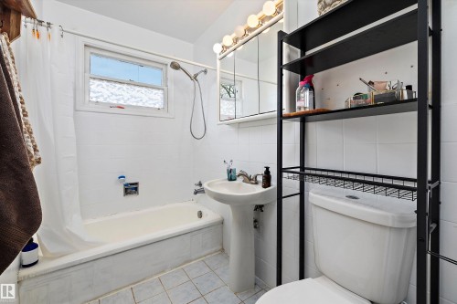 Full bathroom featuring a pedestal sink, white tiled walls, and a window with textured glass - 11607 141 Street, Edmonton, AB - Indoor Photo Showing Bathroom
