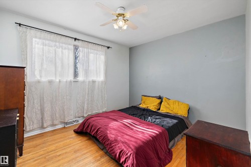 Bedroom featuring wood-finish flooring, a ceiling fan with integrated lighting, and a window with a white sill - 11607 141 Street, Edmonton, AB - Indoor Photo Showing Bedroom