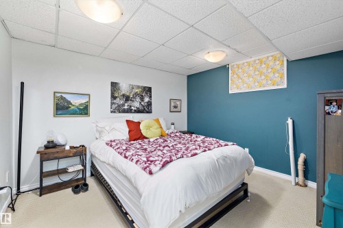 Neutral-toned wall-to-wall carpeting complements the white and accent teal wall finishes - 11607 141 Street, Edmonton, AB - Indoor Photo Showing Bedroom