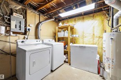 Utility area featuring a top-load washing machine, front-load dryer, chest freezer, and water heater - 
