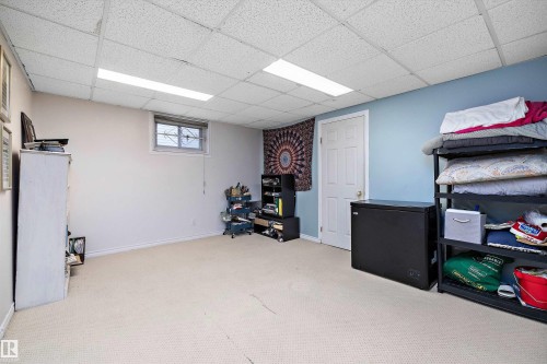 Carpeted flooring, drop ceiling with integrated lighting, window with security bars, white interior door, and two-tone wall paint - 11607 141 Street, Edmonton, AB - Indoor Photo Showing Basement
