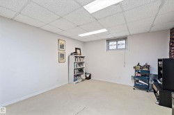 Spacious room with light-toned wall finishes, neutral carpeting, and a drop panel ceiling with fluorescent lighting - 