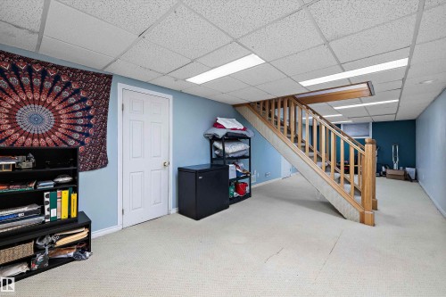 Carpeted interior space with light blue walls and a drop ceiling featuring integrated lighting - 11607 141 Street, Edmonton, AB - Indoor