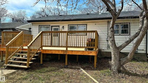 Rear exterior featuring a spacious wooden deck with railings and stairs, white siding, and a dark shingle roof - 11607 141 Street, Edmonton, AB - Outdoor With Deck Patio Veranda