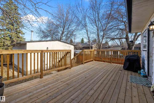 Expansive wood deck with natural wood railings, featuring direct access to the interior and an exterior wall light fixture - 11607 141 Street, Edmonton, AB - Outdoor With Deck Patio Veranda With Exterior
