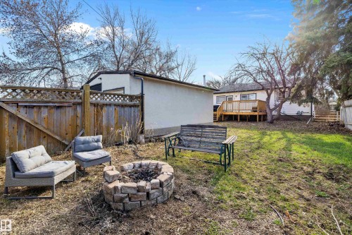 Expansive backyard featuring a stone-ringed fire pit, wood privacy fencing with lattice top, and a raised wood deck - 11607 141 Street, Edmonton, AB - Outdoor With Deck Patio Veranda