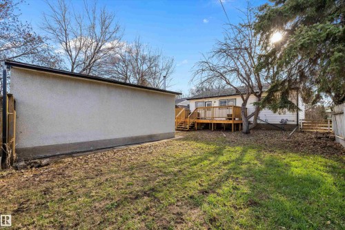 Expansive backyard featuring a large elevated wooden deck with railings, exterior siding, and a detached structure with stucco siding - 11607 141 Street, Edmonton, AB - Outdoor