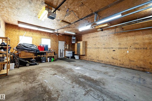 Spacious garage featuring exposed wood-finish walls and ceiling, multiple fluorescent light fixtures, two windows, and a utility sink - 11607 141 Street, Edmonton, AB - Indoor Photo Showing Garage